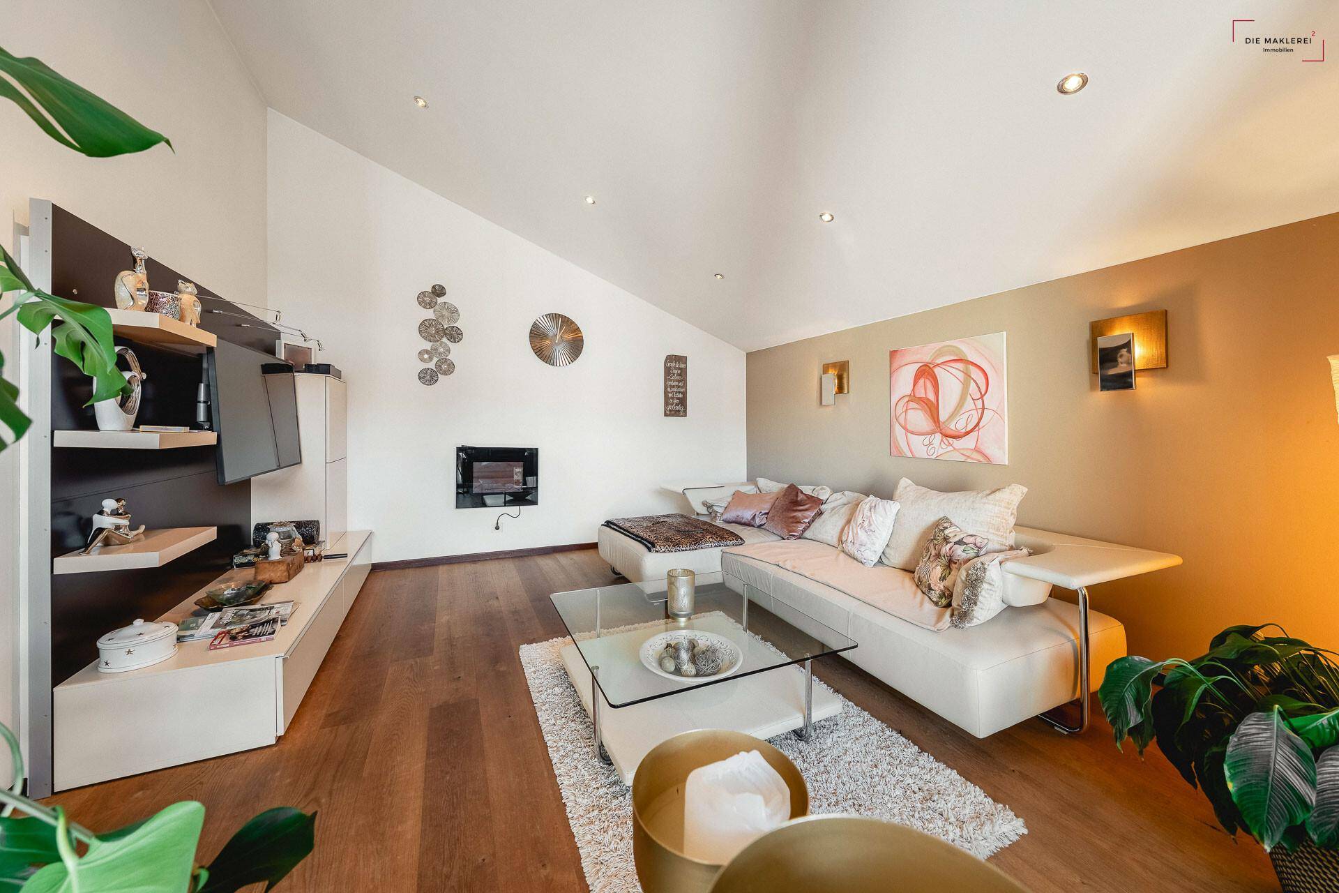 Gemütliches Wohnzimmer mit Dachschräge, großem Sofa, Holzboden und modernem Medienmöbel.