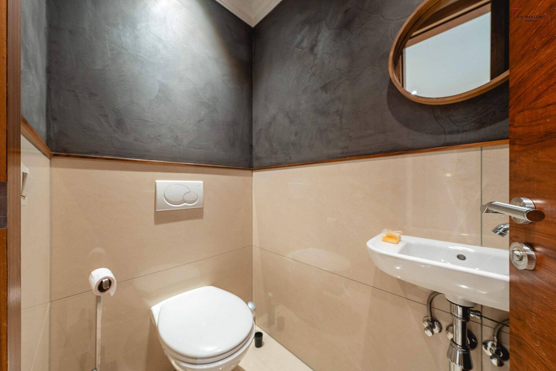 Modernes Gäste-WC mit Wand-WC, kleinem Waschbecken und stilvoller Wandgestaltung in Grau und Beige.