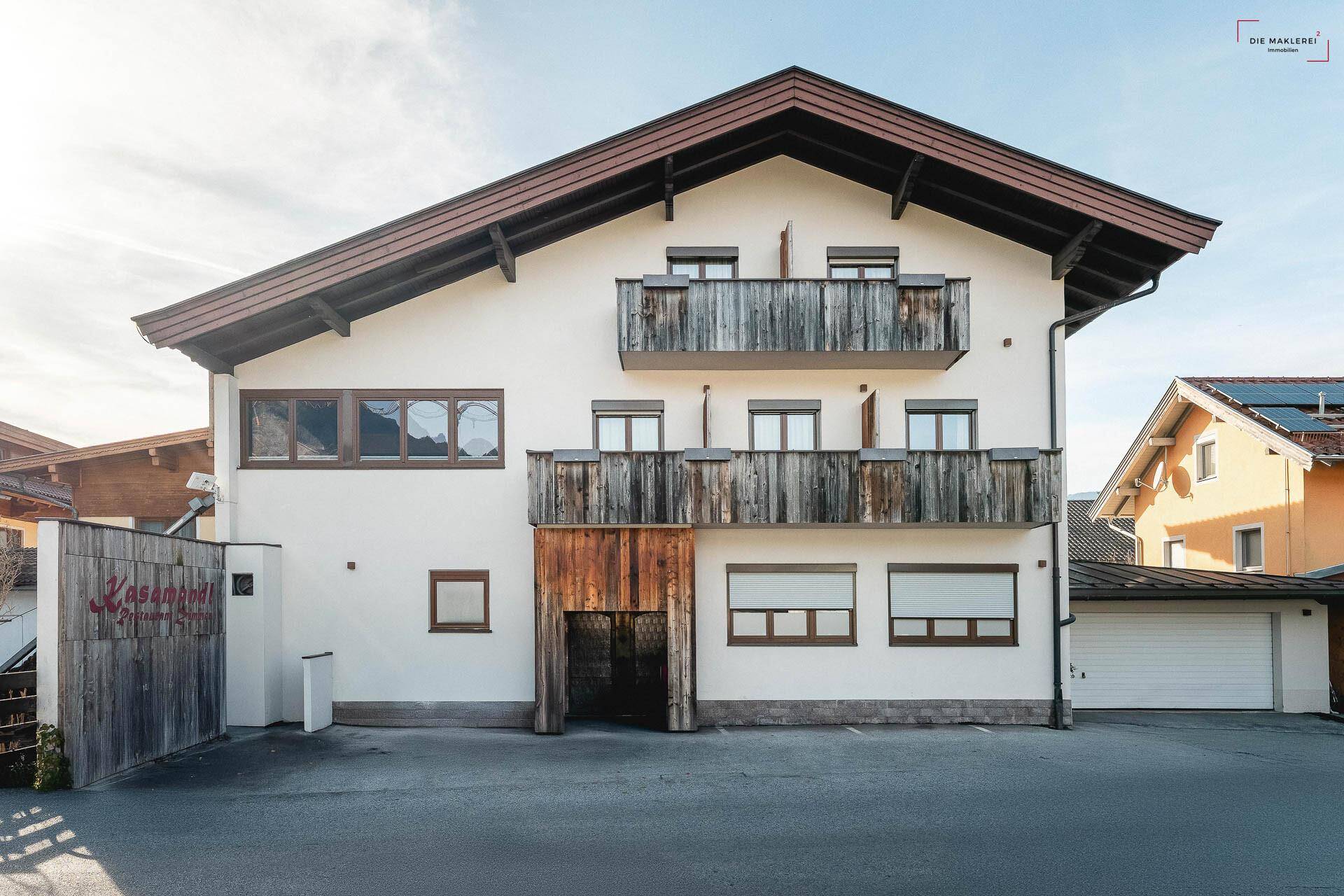 Traditionelles Gebäude mit weißer Fassade, Holzbalkonen und alpiner Architektur.
