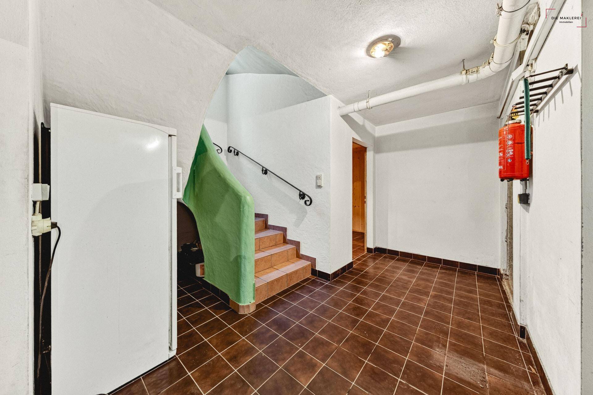 Kellerbereich mit gefliestem Boden, Treppe und Zugang zu weiteren Räumen im Untergeschoss.