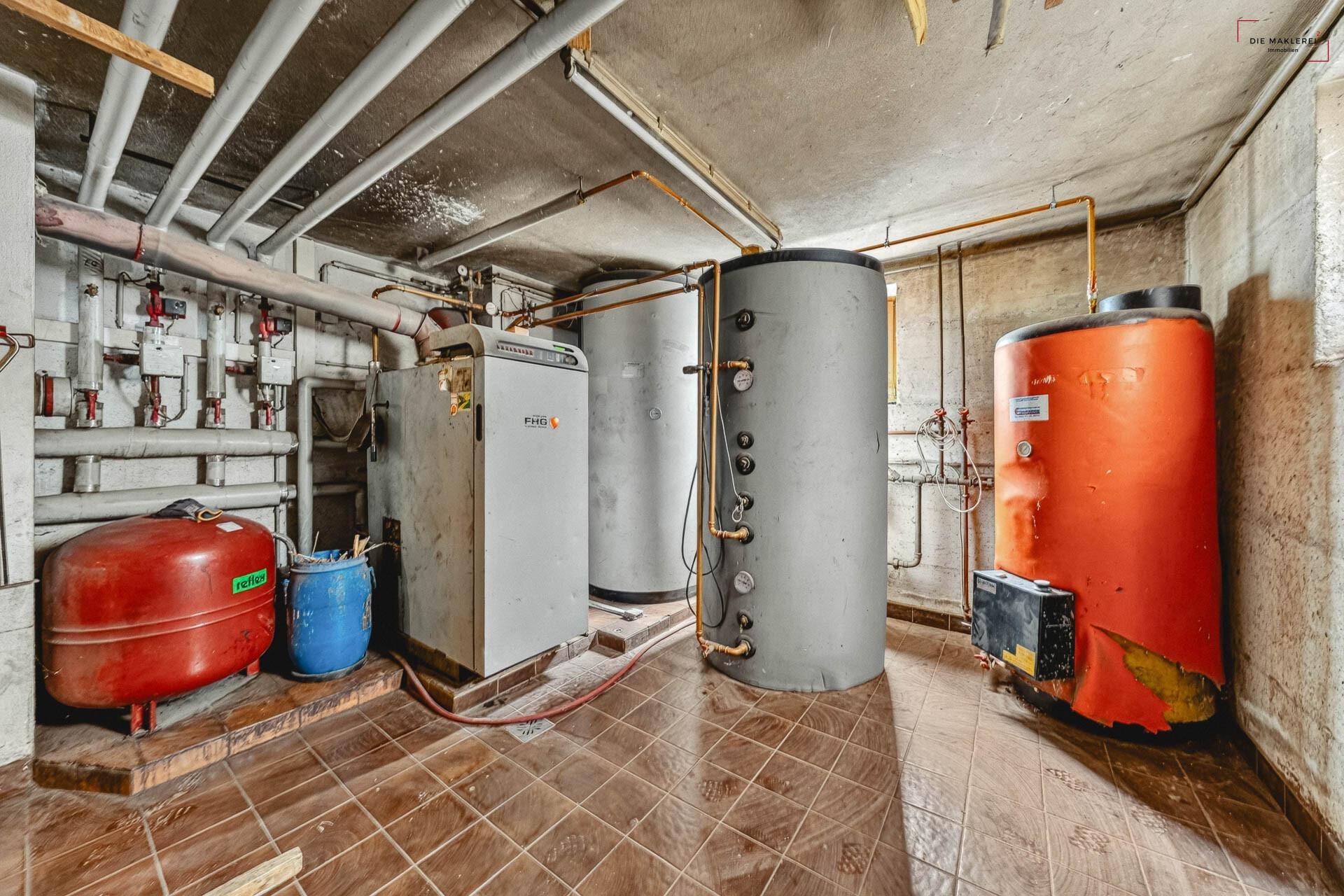 Heizungsraum im Keller mit Kesseln, Rohren und technischen Anlagen für die Wärmeversorgung.