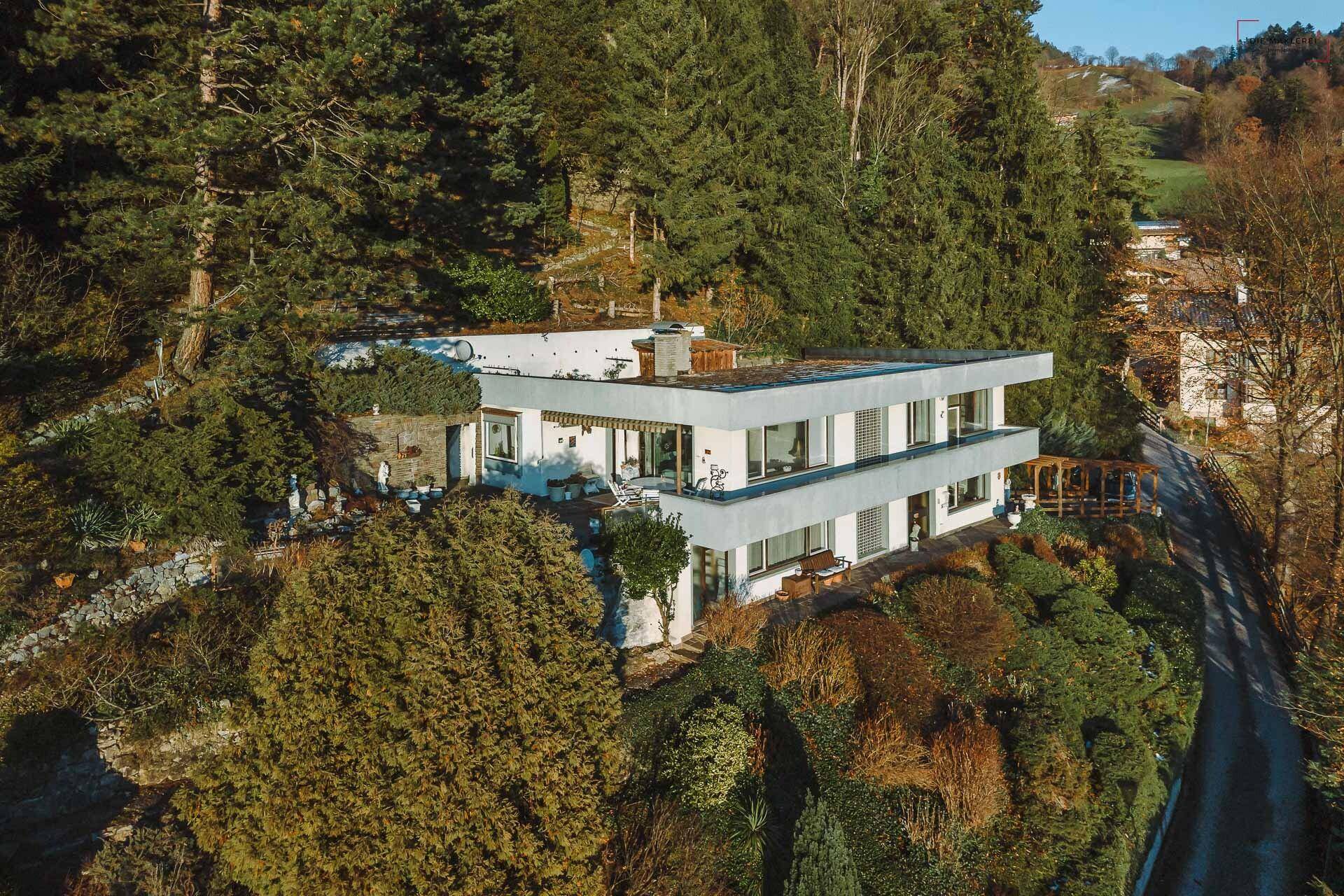 Das moderne Wohnhaus ist harmonisch in die bewaldete Hanglage integriert und bietet eine ruhige Umgebung.