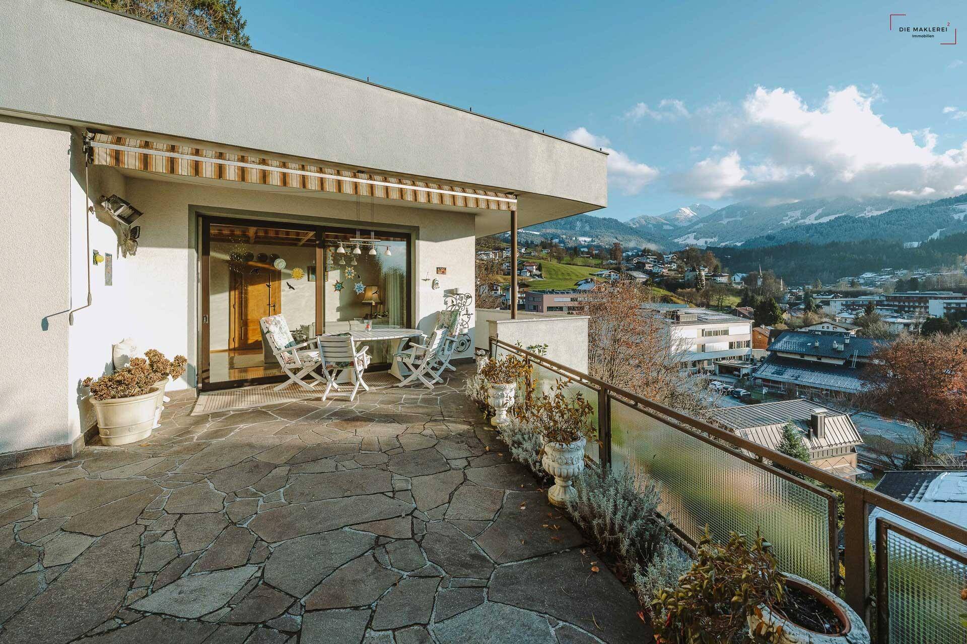 Großzügige Terrasse mit Steinplatten, Gartenmöbeln und einem atemberaubenden Panoramablick auf die Berge.