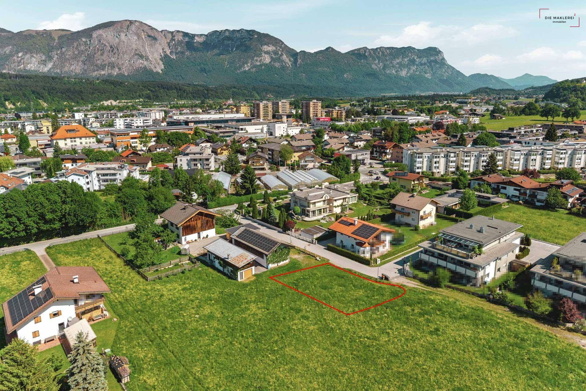 Panoramablick auf ein Baugrundstück in ländlicher Umgebung mit Bergen im Hintergrund.
