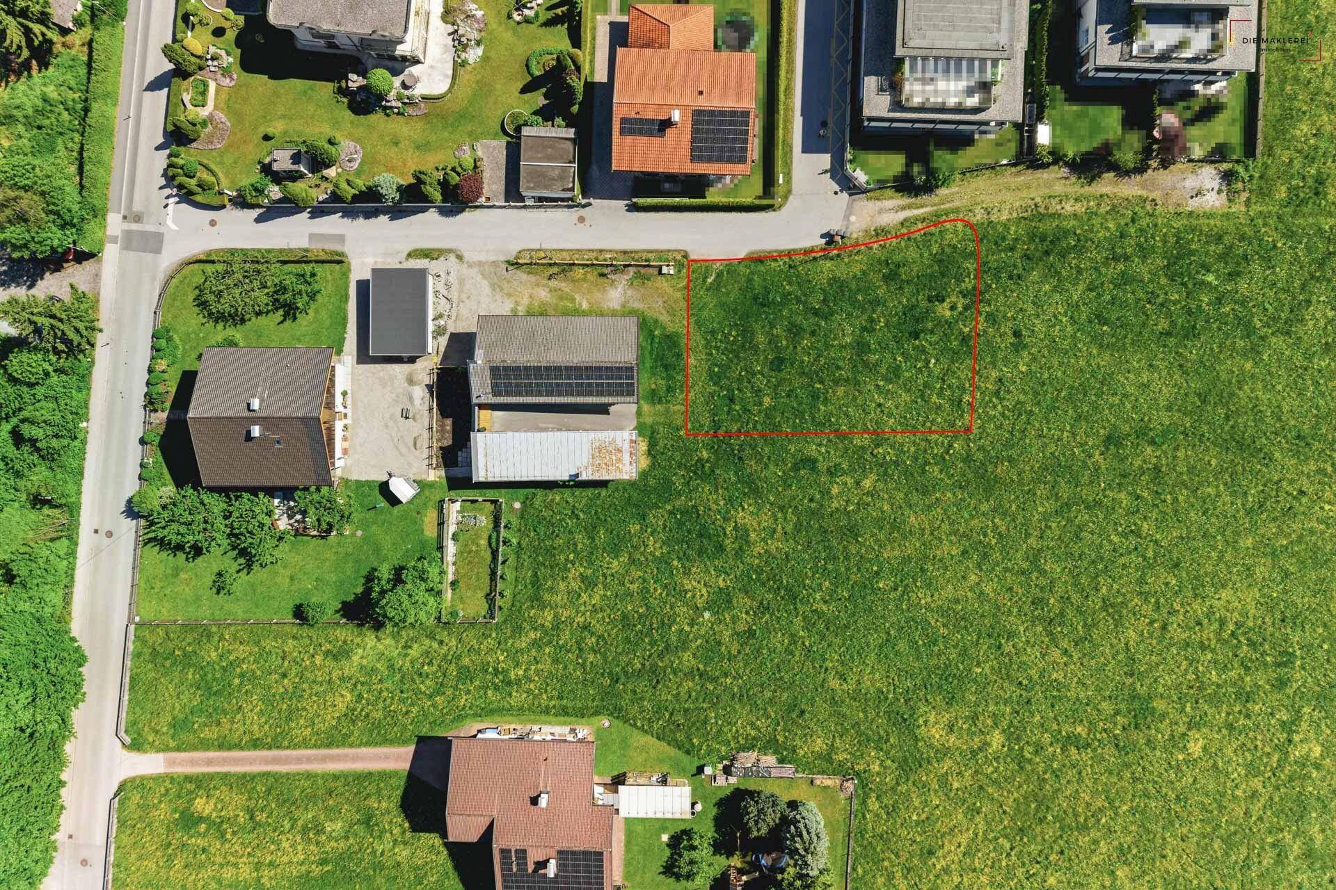 Senkrechte Luftaufnahme eines Baugrundstücks mit angrenzenden Häusern und Zufahrtsstraße.