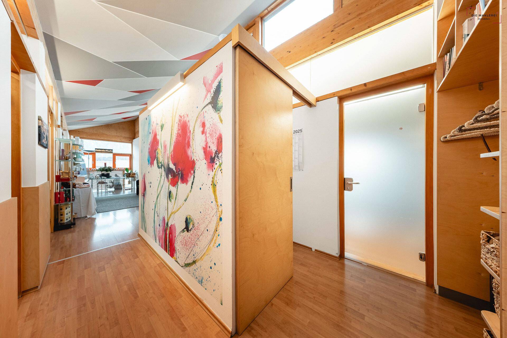 Heller Flur mit Holzboden, künstlerischer Wandgestaltung und hohen Decken, der zu weiteren Räumen führt.