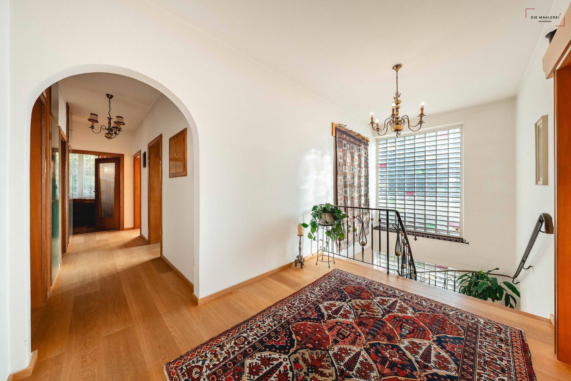 Oberer Flur mit Holzboden, einem dekorativen Teppich und Blick auf die untere Etage.