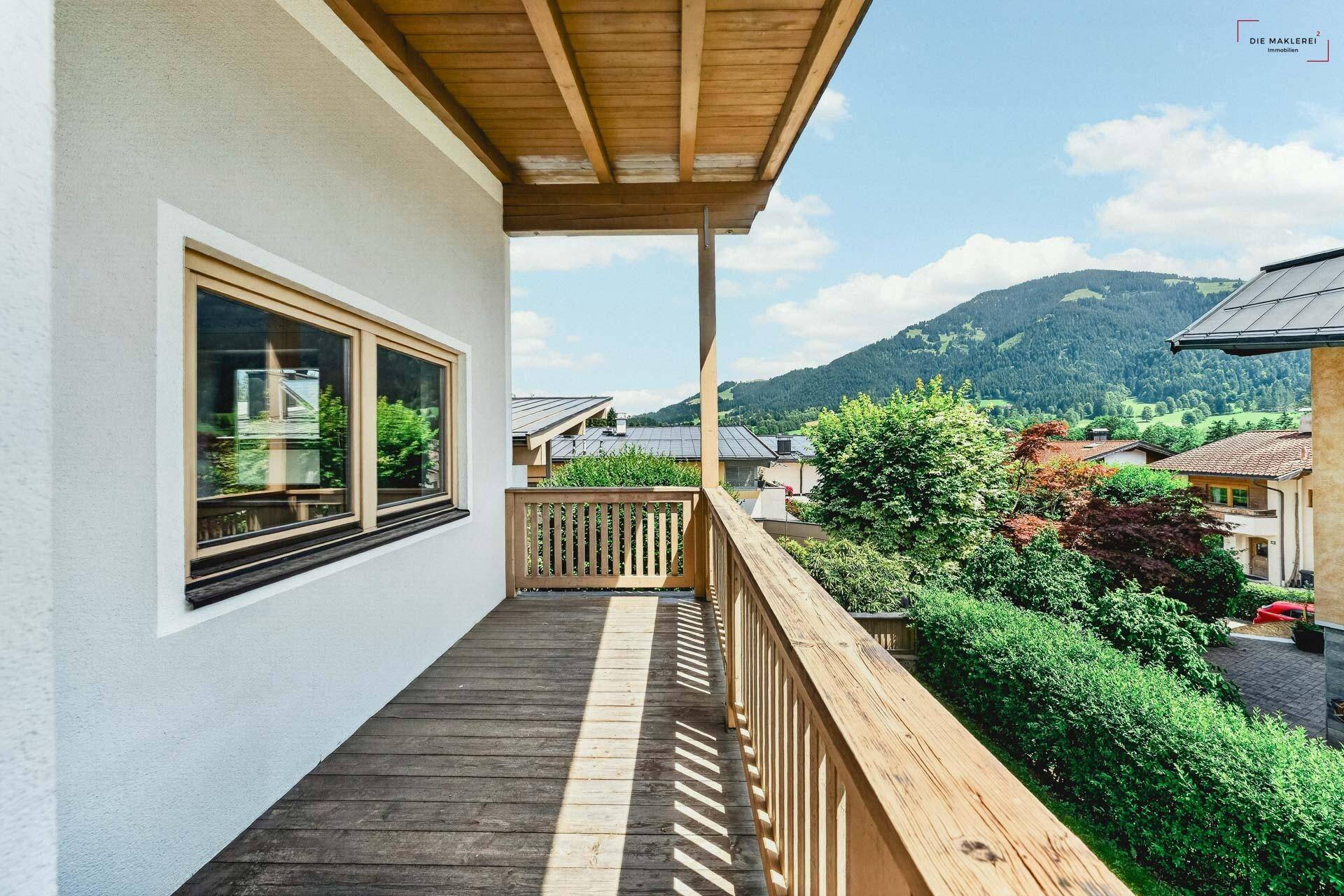 Sonniger Holzbalkon mit Geländer und weitem Blick auf die umliegende Berglandschaft.