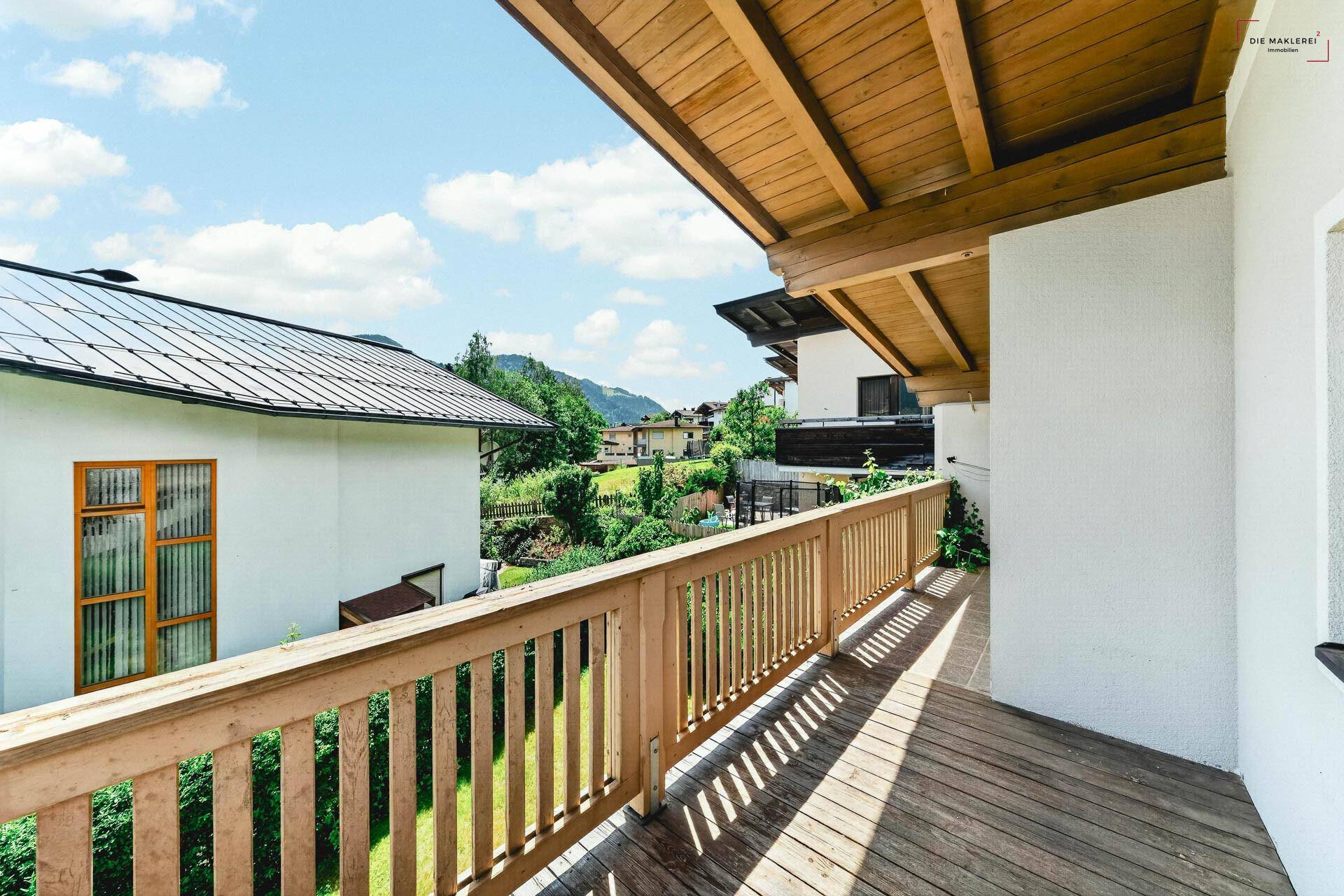 Geräumiger Holzbalkon mit Blick auf die Nachbarschaft und grüne Umgebung.