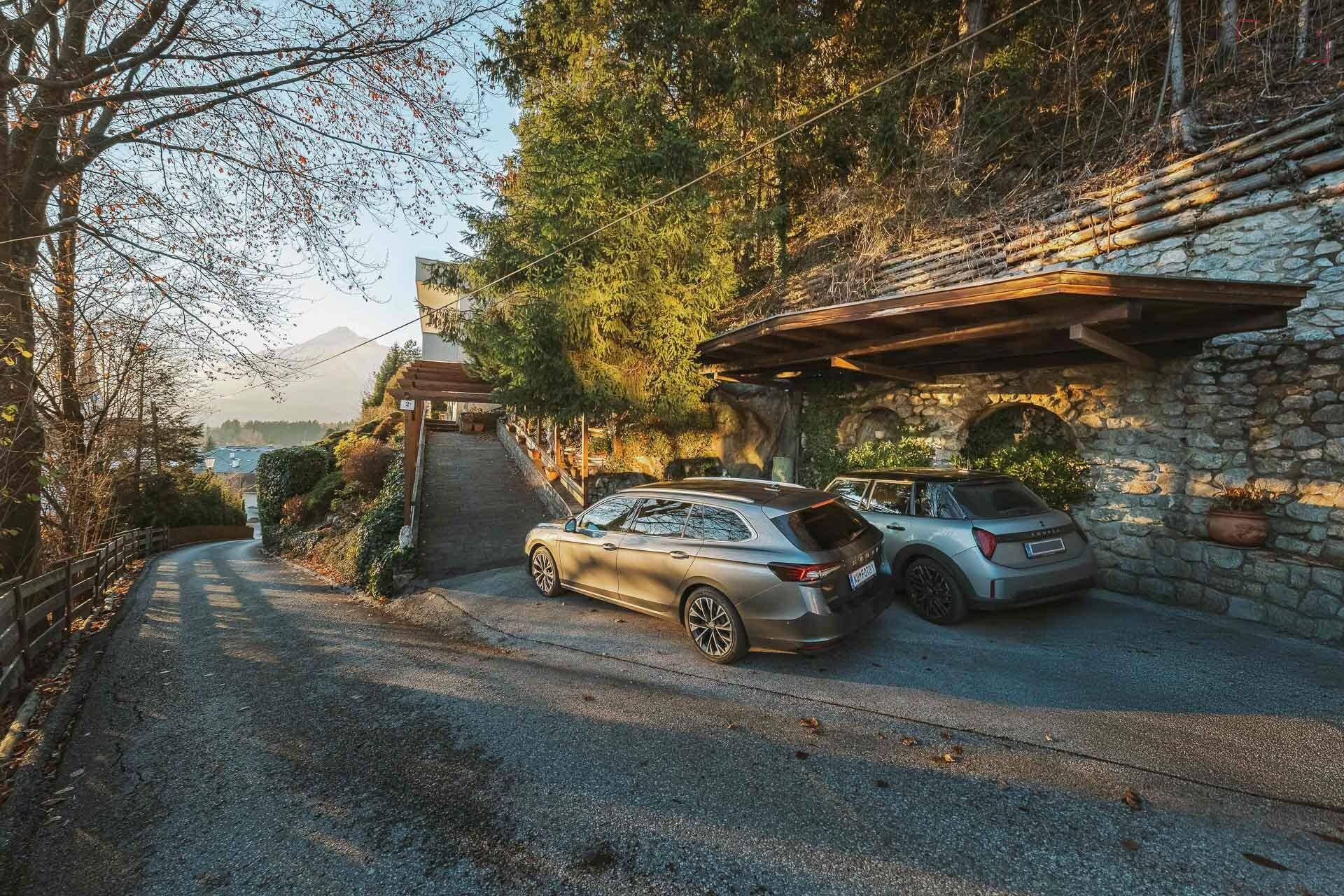Überdachte Parkplätze unter einem Carport, integriert in eine robuste Steinmauer.