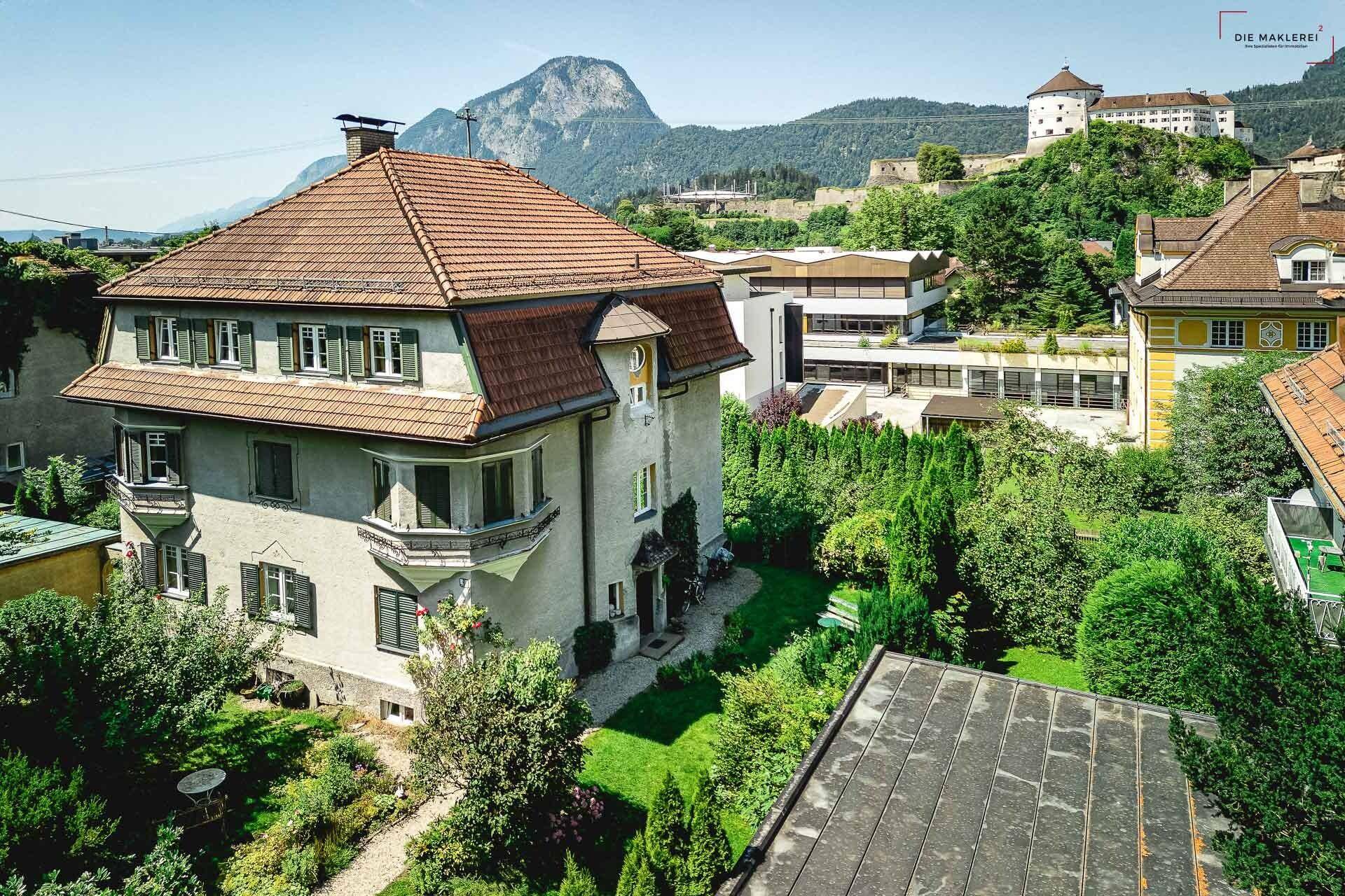 Eindrucksvolles Stadthaus mit Garten, umgeben von Bergen und einer historischen Burg.