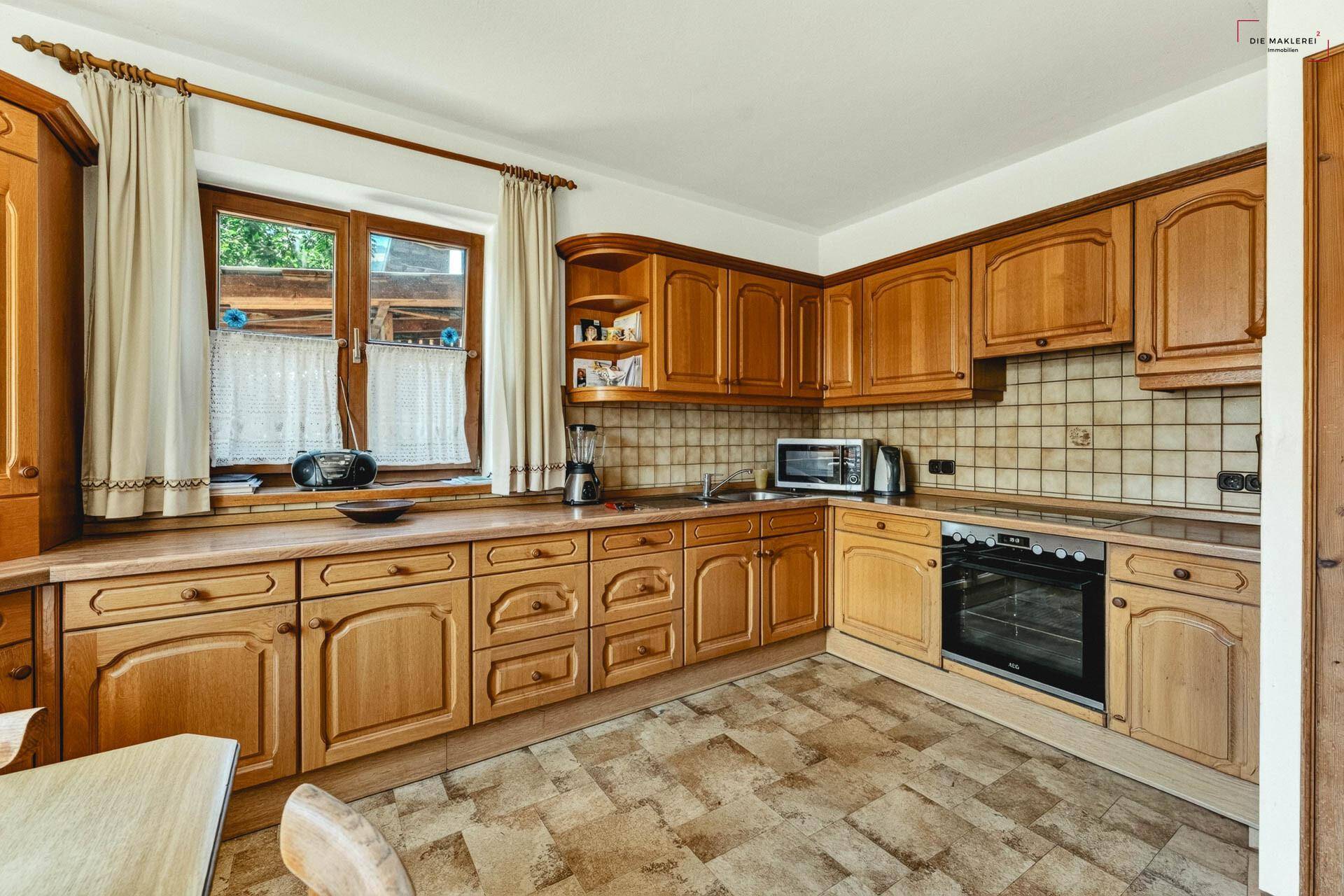 Funktionale Küche mit Holzschränken, Fliesenrückwand und integrierten Geräten im Landhausstil.