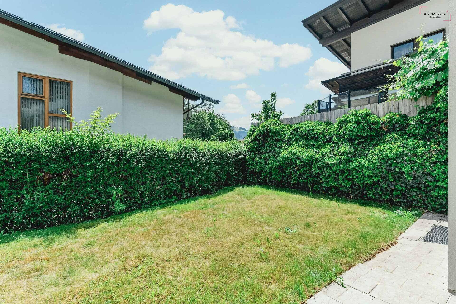 Privater Gartenbereich mit Rasenfläche und hohen Hecken für Sichtschutz.