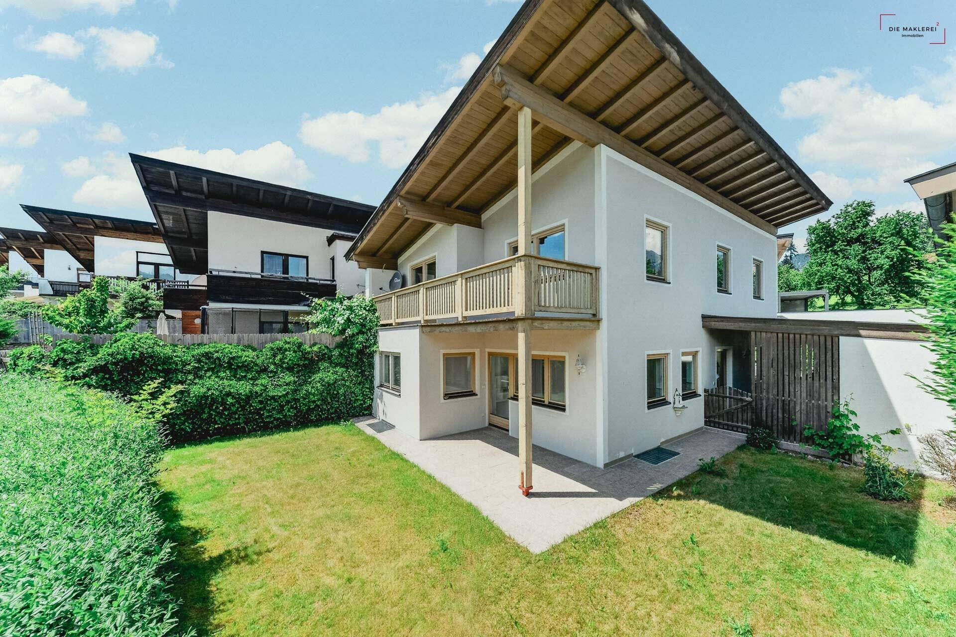 Rückansicht des Hauses mit Balkon, Terrasse und gepflegtem Garten.