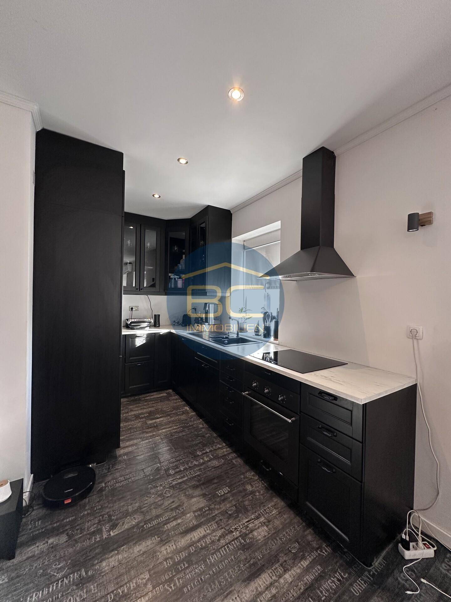 Elegante schwarze Küche mit modernen Geräten, Induktionskochfeld und Marmor-Arbeitsplatte.