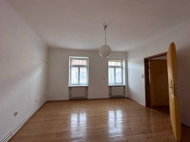 Geräumiger Raum mit Holzdielenboden und weiß gestrichenen Wänden.