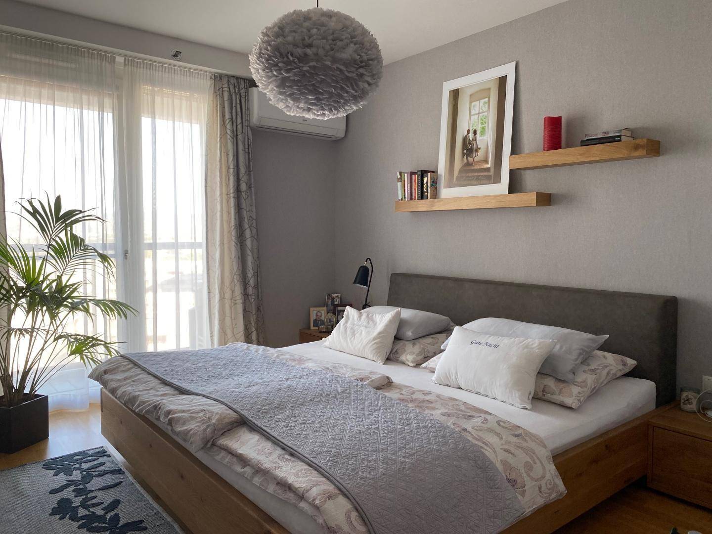 Gemütliches Schlafzimmer mit Doppelbett, Holzboden und großen Fenstern.