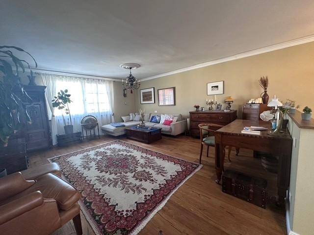 Helles Wohnzimmer mit Holzboden, Sofa und einem antiken Schreibtisch.