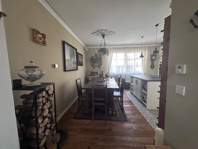 Gemütlicher Essbereich mit Holztisch, Parkettboden und einem dekorativen Holzstapel.