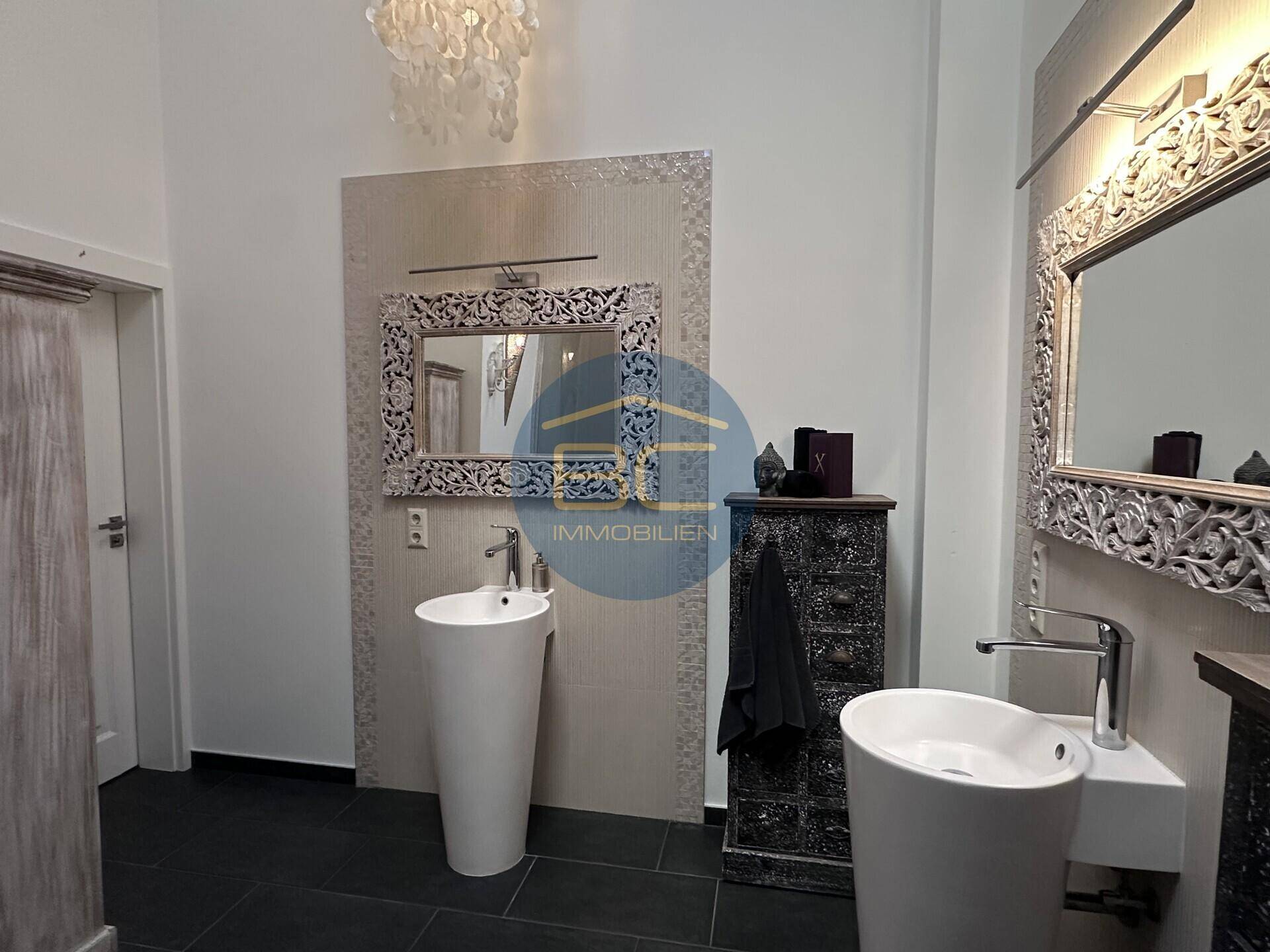 Elegantes Badezimmer mit zwei modernen Waschbecken und dekorativen Spiegeln.