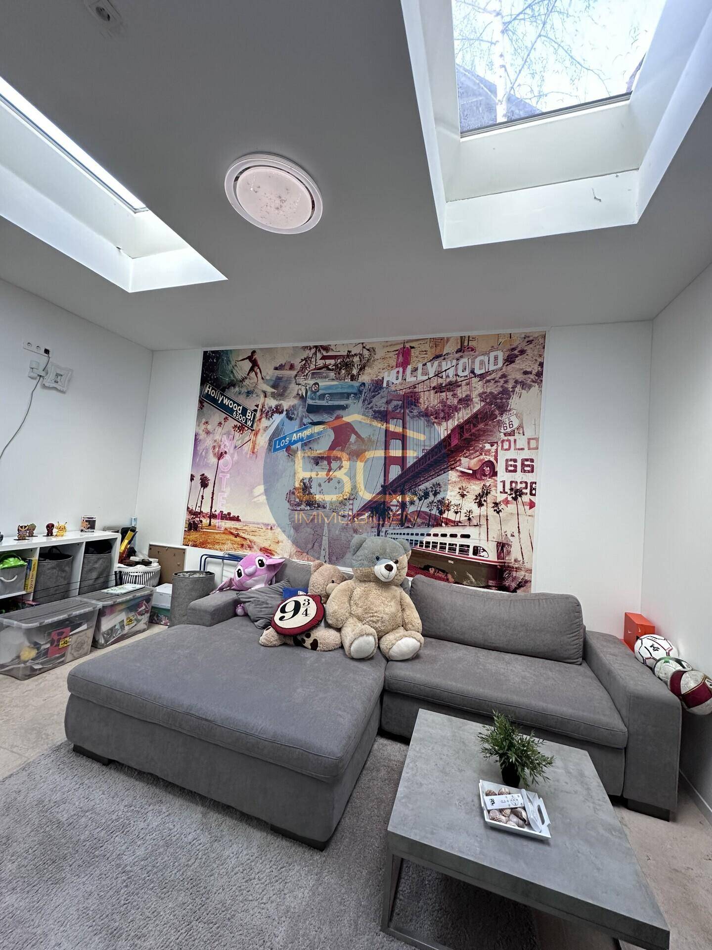 Helles Wohnzimmer mit großem Sofa, Couchtisch und Oberlichtern für viel Tageslicht.
