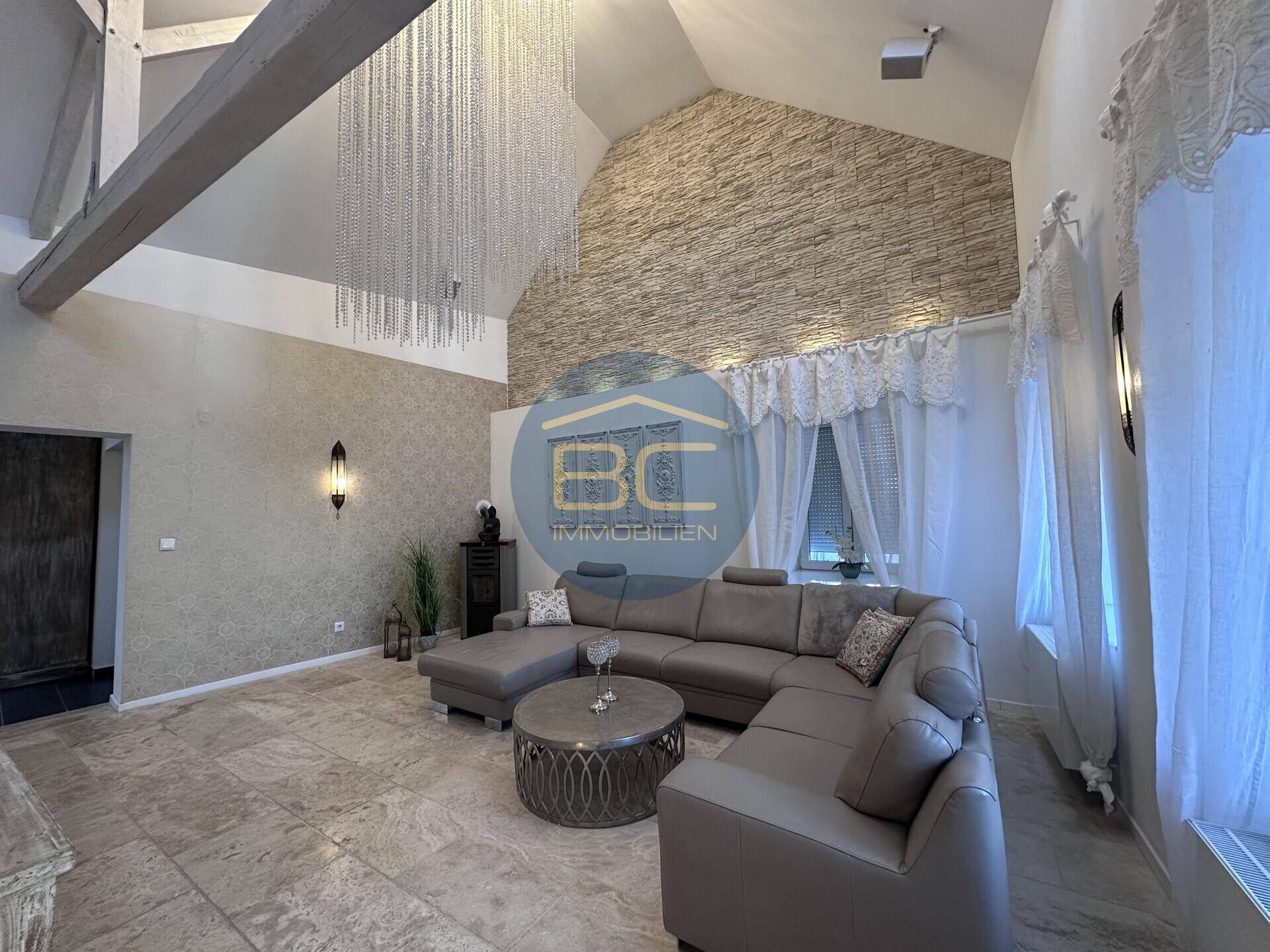 Geräumiges Wohnzimmer mit großem Ecksofa, dekorativer Steinwand und hoher Decke.