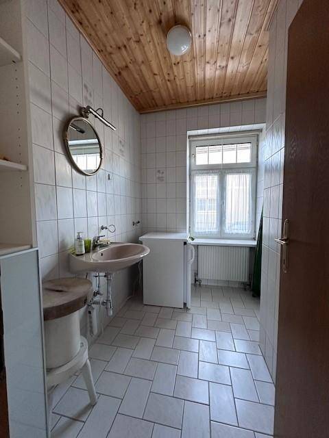 Praktischer Raum mit Fliesenboden, Waschbecken und Platz für eine Waschmaschine.