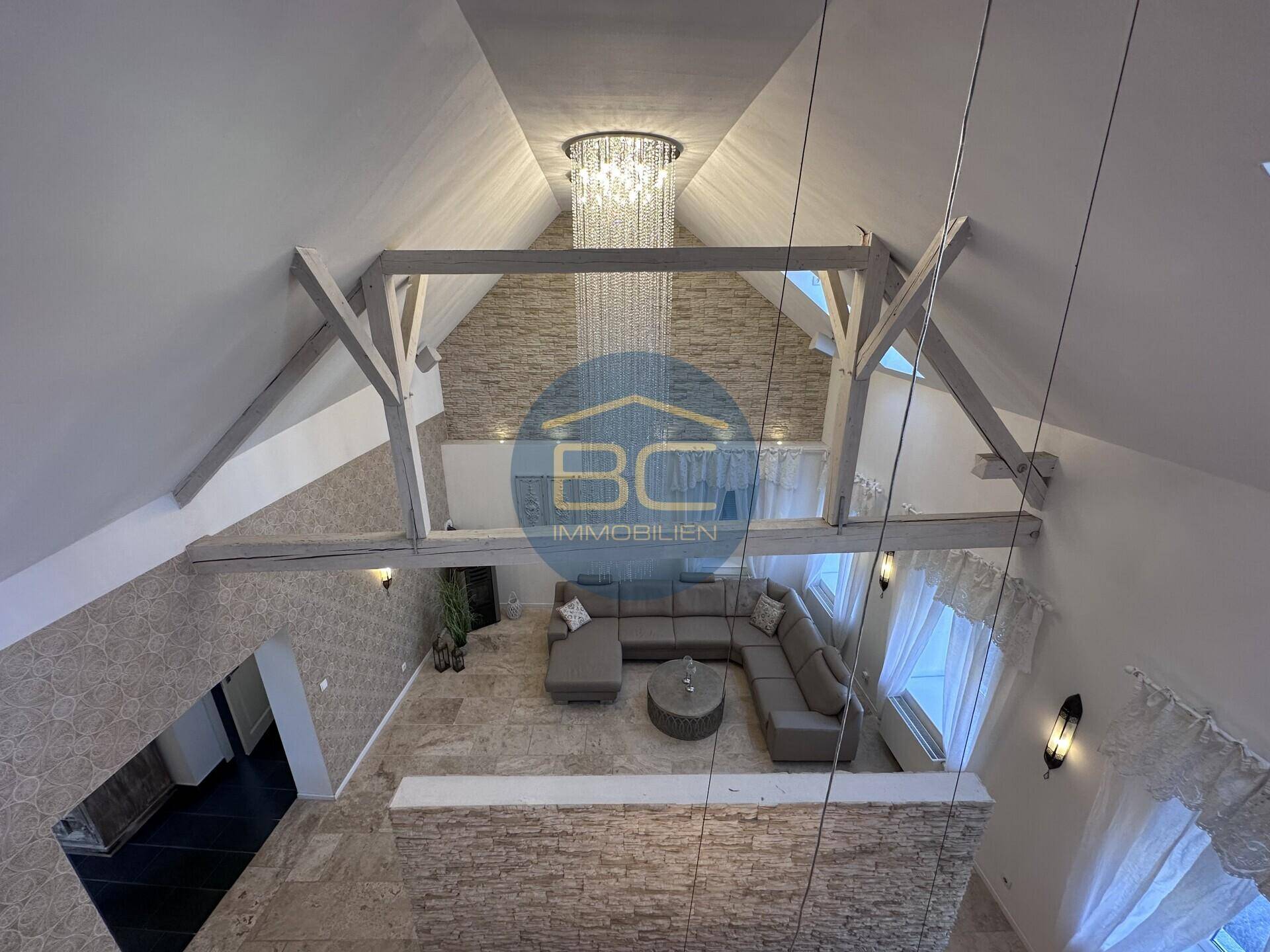 Blick von oben auf den offenen Wohnbereich mit hohen Decken und elegantem Kronleuchter.