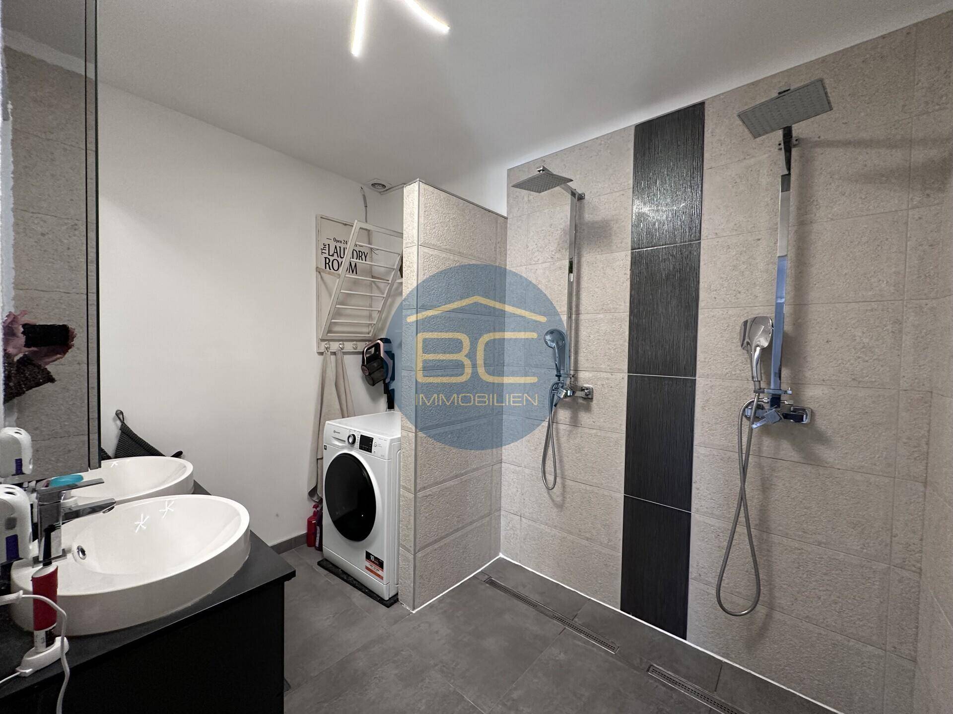 Modernes Badezimmer mit zwei Regenduschen und integrierter Waschmaschine.