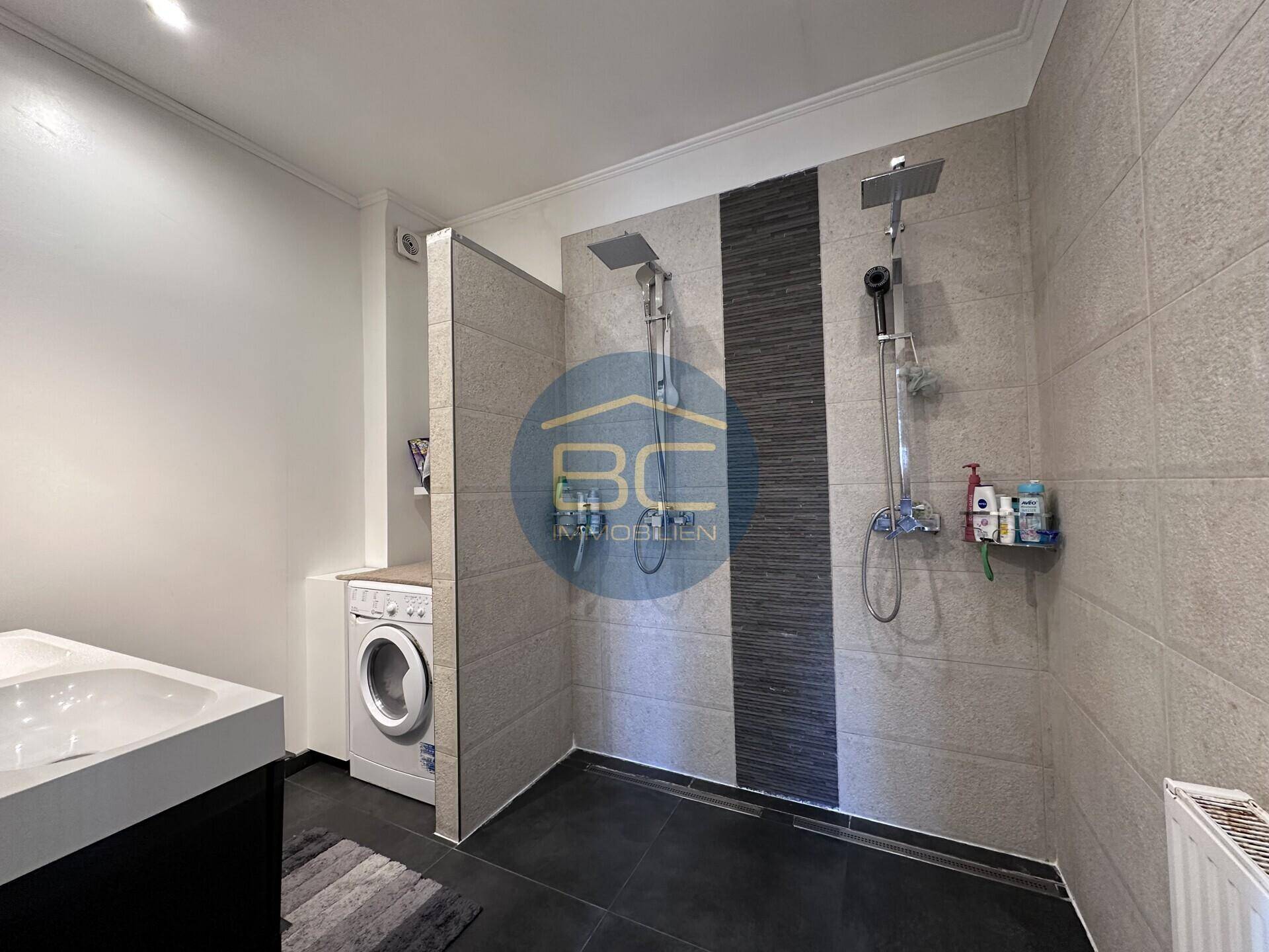 Modernes Badezimmer mit zwei Regenduschen und integrierter Waschmaschine.