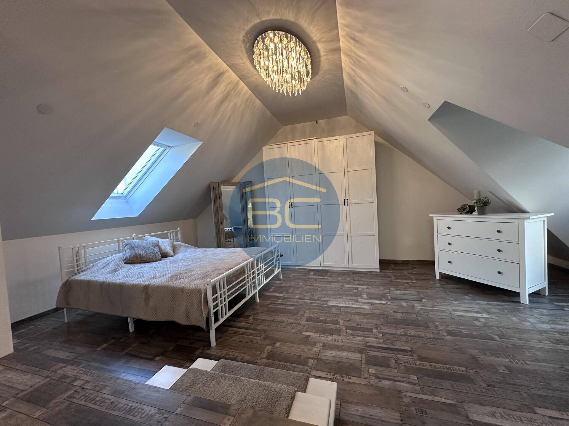Gemütliches Schlafzimmer im Dachgeschoss mit Dachfenster, Holzboden und Einbauschrank.