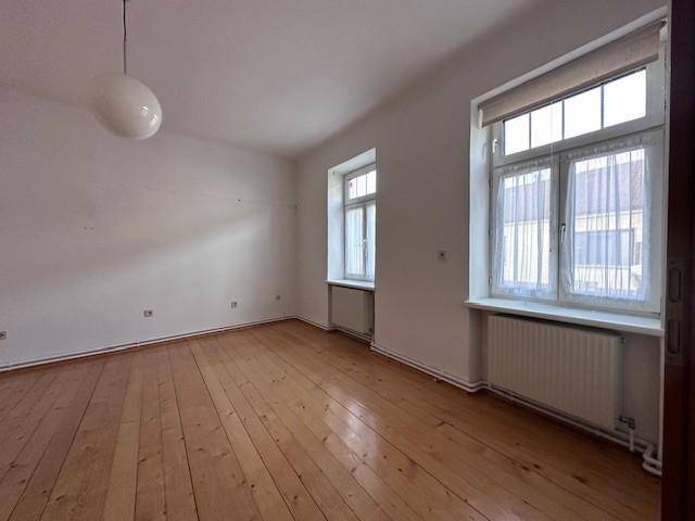 Heller Raum mit Holzdielenboden und zwei Fenstern für viel Tageslicht.