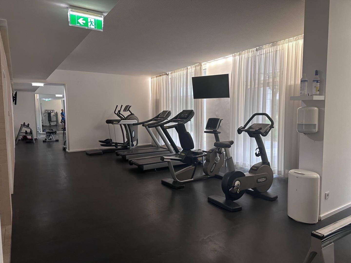 Moderner Fitnessraum mit Laufbändern, Fahrrädern und weiteren Trainingsgeräten.