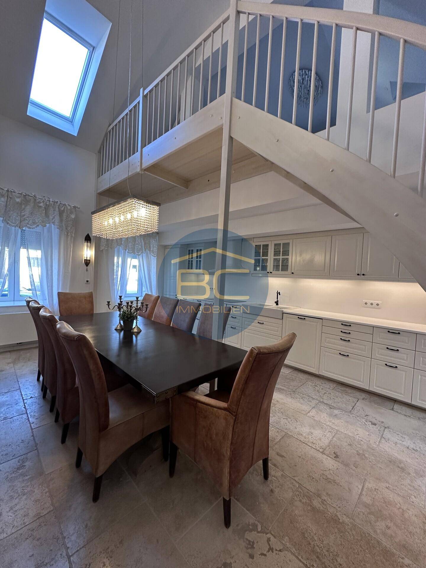 Geräumiger Essbereich mit großem Tisch und Blick auf die offene Küche und Treppe.