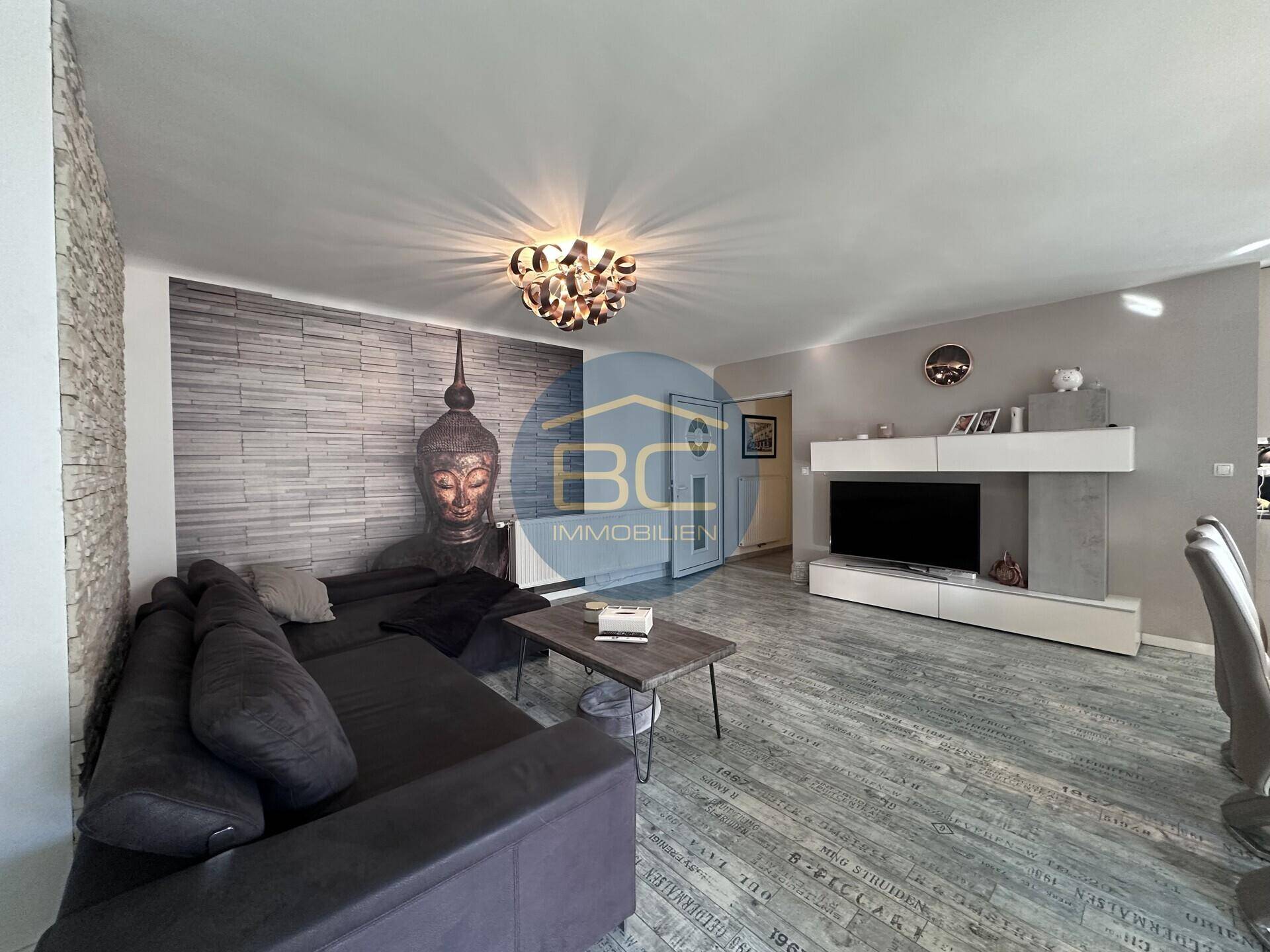 Moderner Wohnbereich mit großem Sofa, TV-Möbel und dekorativer Buddha-Wand.