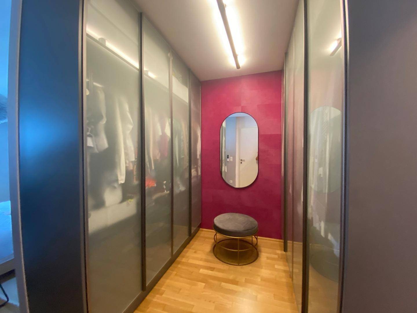 Geräumiger begehbarer Kleiderschrank mit integrierten Schränken und Spiegel.