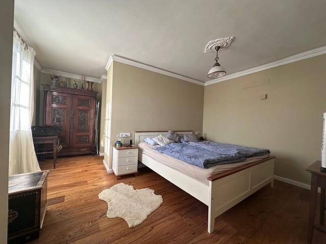 Gemütliches Schlafzimmer mit Holzboden, Doppelbett und traditionellem Kleiderschrank.