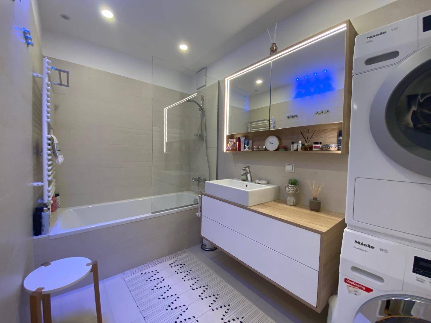 Modernes Badezimmer mit Badewanne, Dusche, Einzelwaschbecken und Waschmaschine/Trockner.