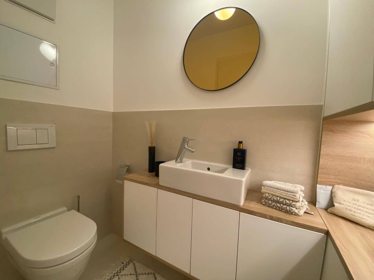 Modernes Gäste-WC mit stilvollem Waschbecken, Spiegel und Wand-WC.