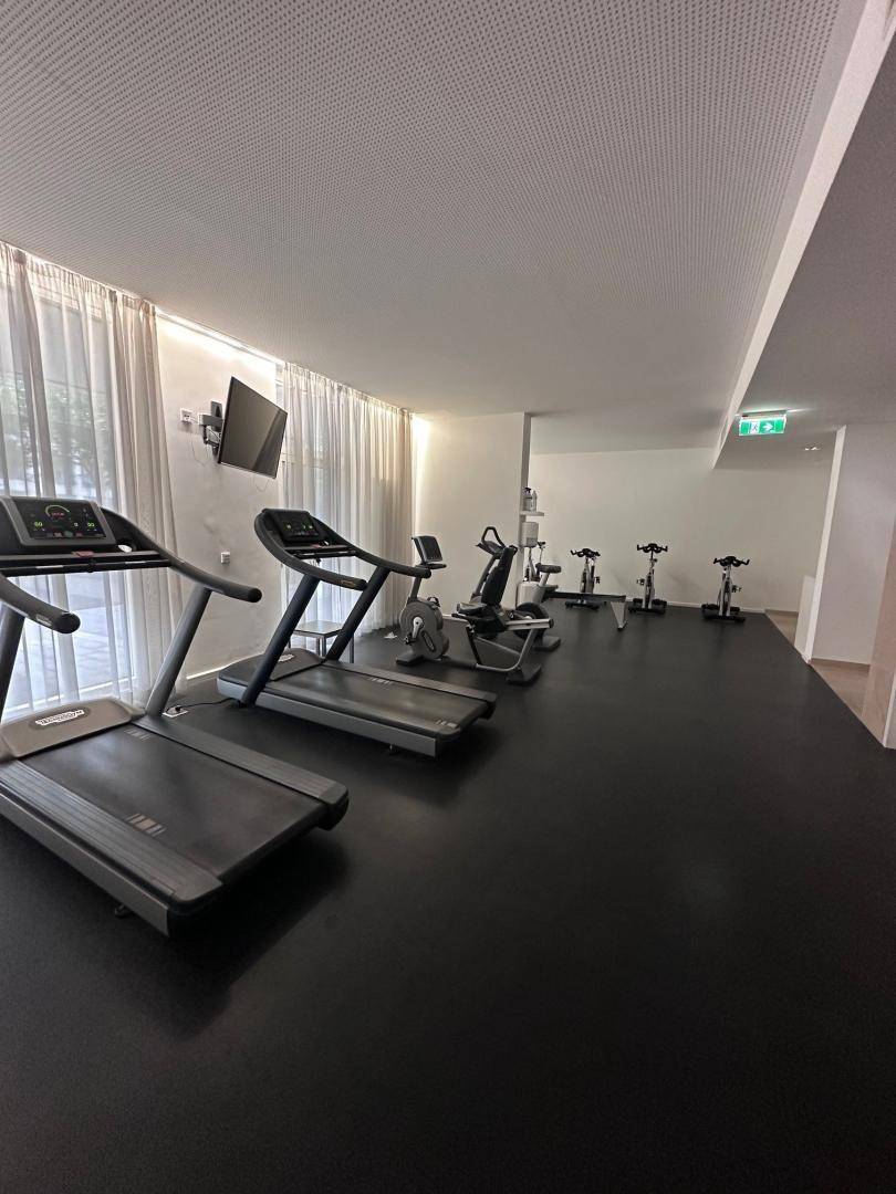 Gut ausgestatteter Fitnessraum mit mehreren Laufbändern und Fahrrädern.