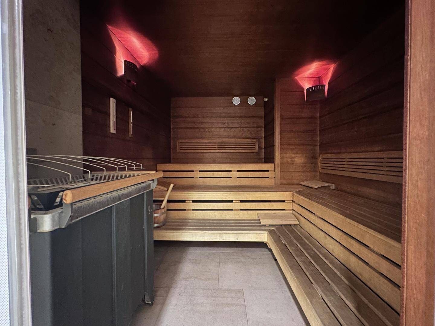 Geräumige Holzsauna mit Bänken und Heizofen für entspannende Momente.