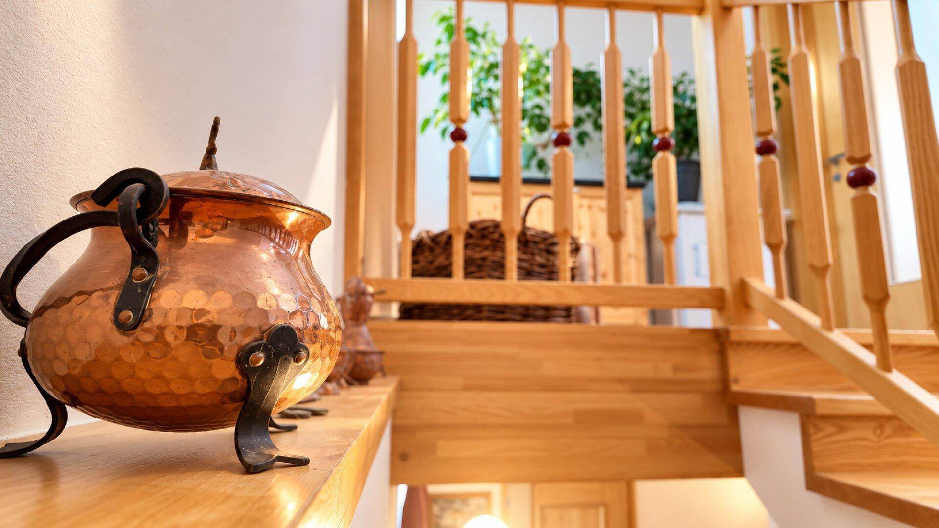 Detailansicht eines Kupfertopfes auf einem Holzgeländer einer Treppe in traditionellem Stil.