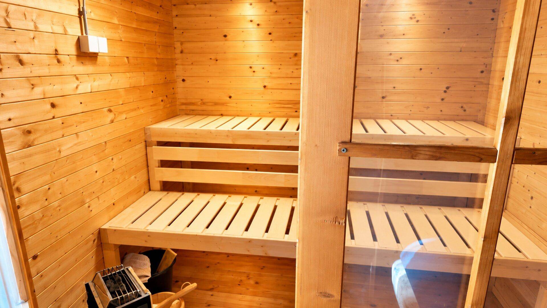 Geräumige Holzsauna mit mehreren Bänken und einem Saunaofen, ideal für Wellness.