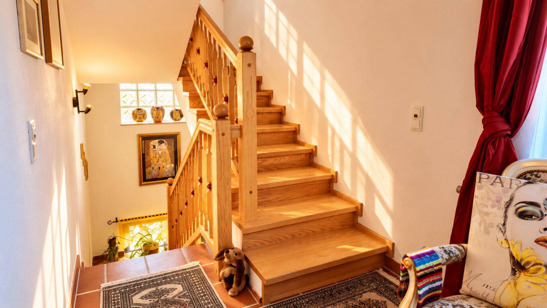 Helles Treppenhaus mit Holztreppe und Geländer, das viel natürliches Licht empfängt.