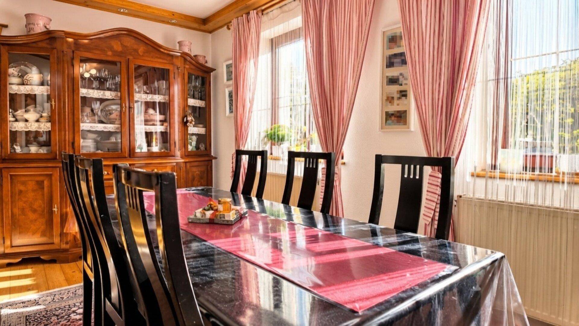 Traditioneller Essbereich mit großem Holztisch, dunklen Stühlen und einem antiken Holzschrank.