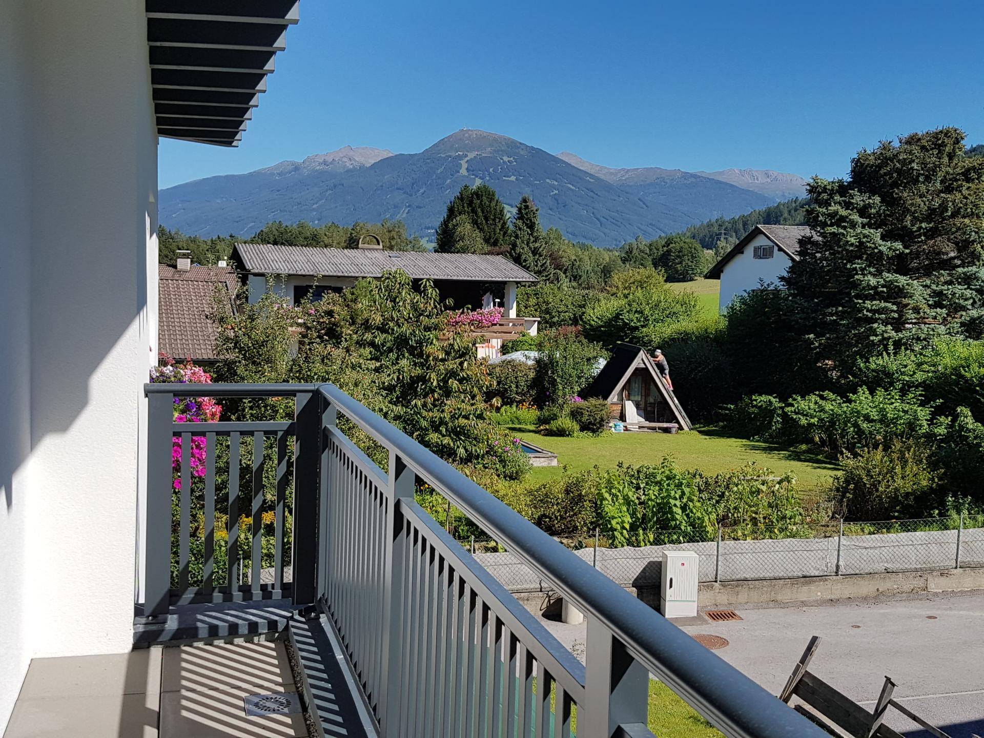 Balkon mit weitem Blick auf die umliegende Berglandschaft und grüne Umgebung.