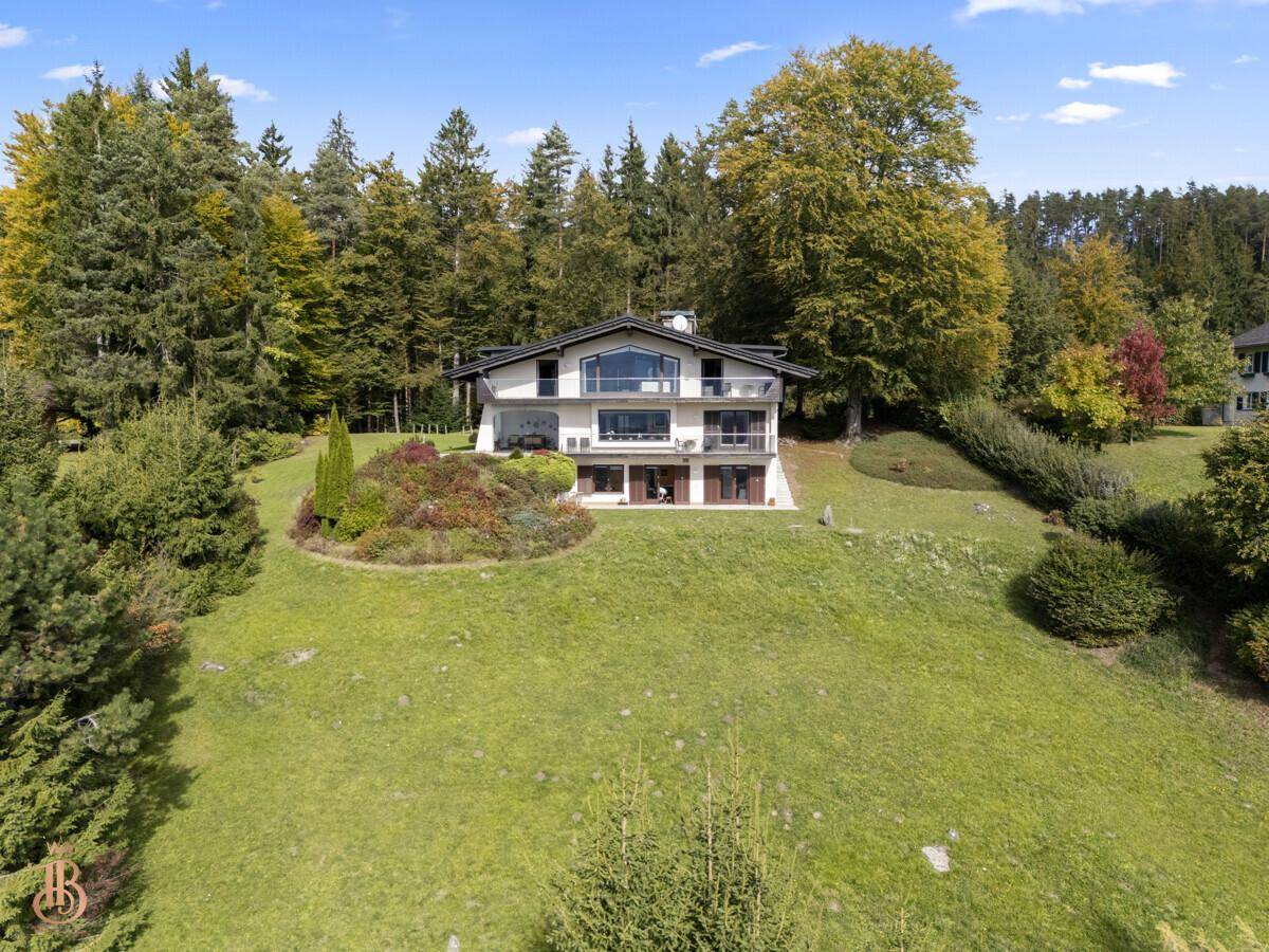 Großzügiges Anwesen mit moderner Architektur, umgeben von üppiger Natur und Wald.