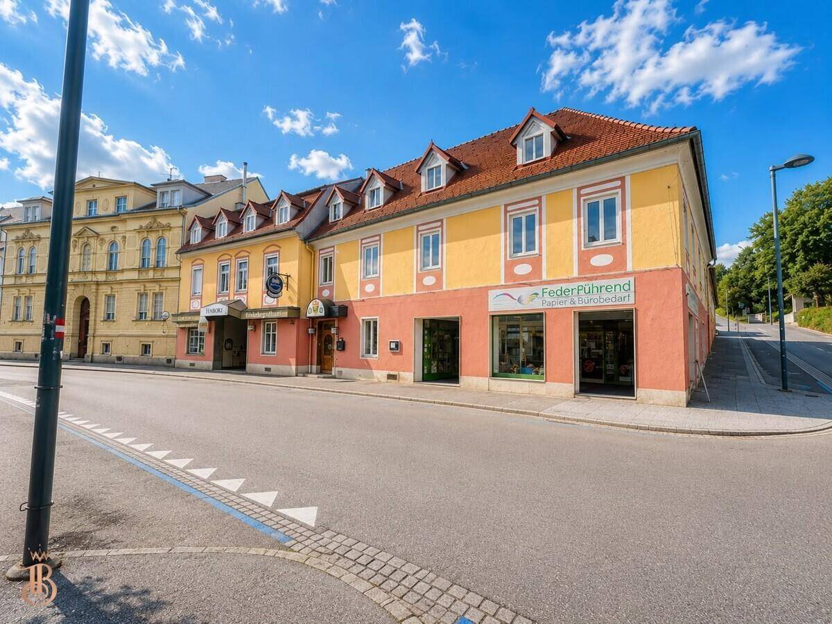 Breite Ansicht des Gebäudes an einer Straßenecke mit Geschäften und Wohnungen.