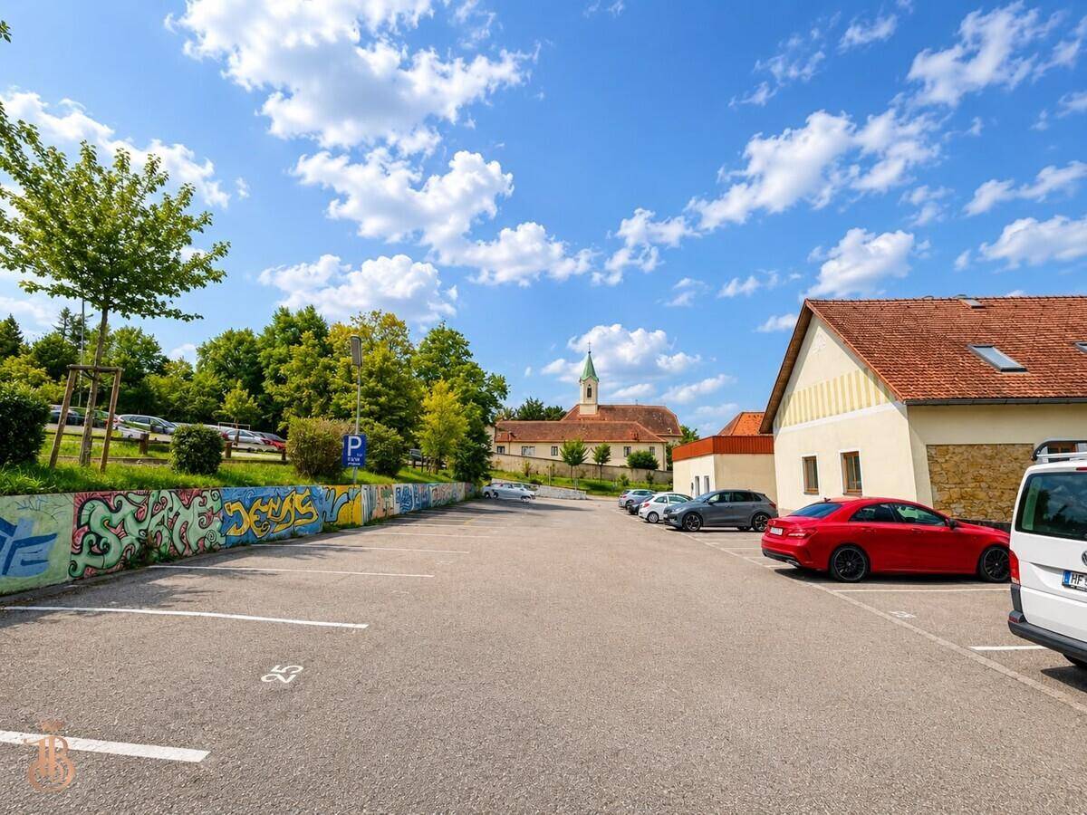 Außenparkplatz mit bunter Graffiti-Mauer und Blick auf eine Kirche im Hintergrund.