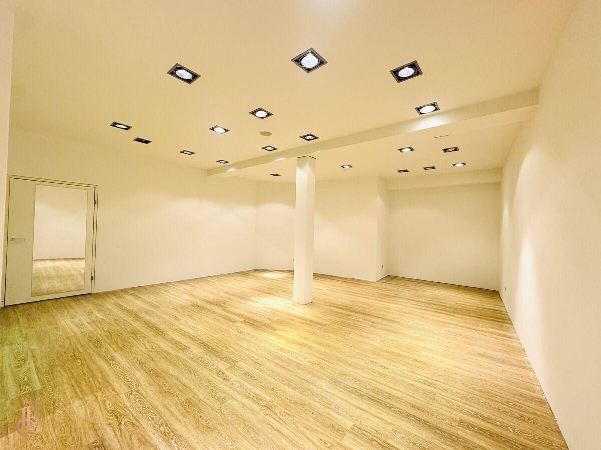 Großer, heller Raum mit Holzboden, Säule und moderner Deckenbeleuchtung.